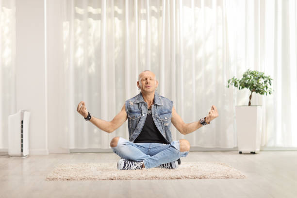 istock Man in jeans seated on a carpet practicing meditation in a living room 1413572297