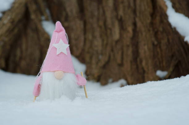 A toy gnome on skis in the winter forest. Christmas figurines.