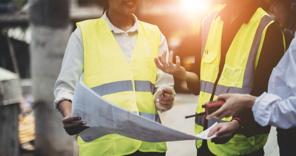 istock Three experts inspect commercial building construction sites and construction site holding blueprints 1413572682