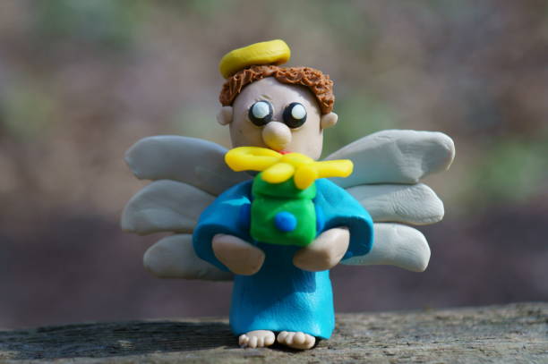 A toy angel with a gift box. Toys made of plasticine. Christmas decorations. New Year's mood.
