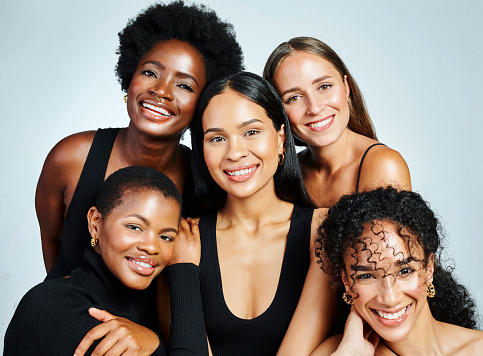 Group of diverse and happy women showing beauty, skincare and cosmetics while posing together against a grey studio background. Portrait of female models showing their perfect and bright smiles