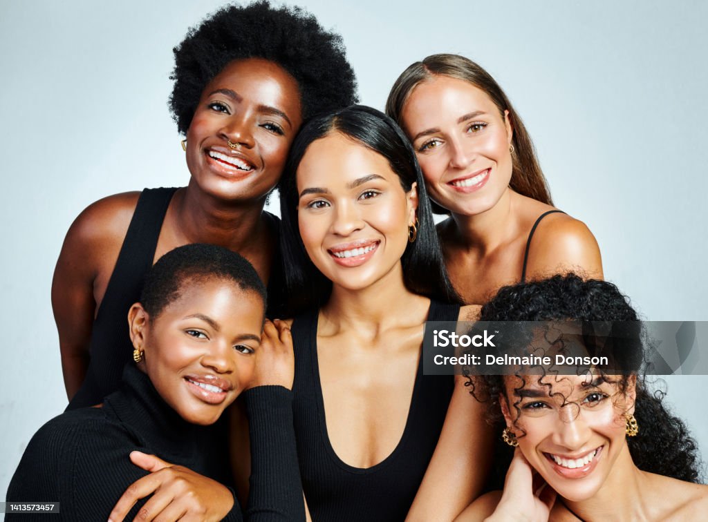 Group of diverse and happy women showing beauty, skincare and cosmetics while posing together against a grey studio background. International female portrait of empowered women with bright smiles Group of diverse and happy women showing beauty, skincare and cosmetics while posing together against a grey studio background. Portrait of female models showing their perfect and bright smiles Women Stock Photo