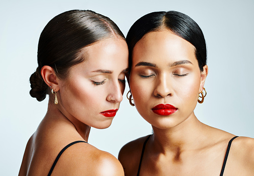 Beautiful, diverse young ladies showing how the same makeup look on different skin. Portrait of two fresh, healthy women with red lipstick. Closeup of relaxed faces with a great skincare routine