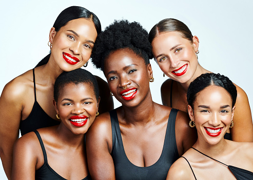 Happy, smiling and beautiful group of women posing, showing makeup and huddling together against a white studio background. Portrait of a group of female models looking cheerful, joyful and pretty
