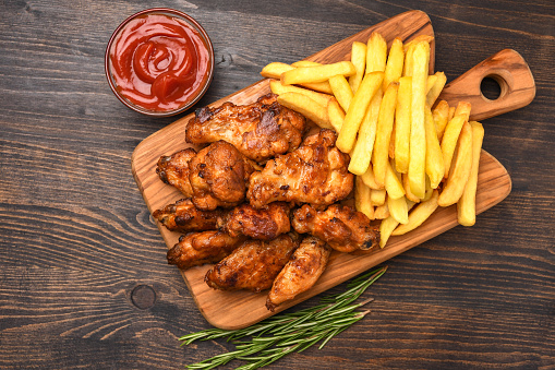 Spicy chicken wings with potatoes fries and ketchup.