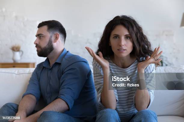 Annoyed Married Couple Sitting On Couch Apart After Conflict Stock Photo - Download Image Now