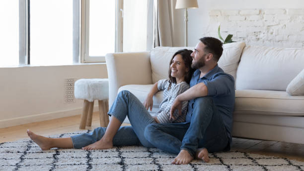 Happy joyful married couple resting on warm carpeted floor