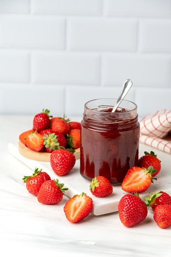 Bio Strawberry jam in glass jar at white table and Fresh Strawberries, vegan food  gluten free