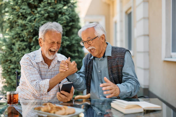 Cheerful senior men having fun while using  laptop on a terrace at nursing home.