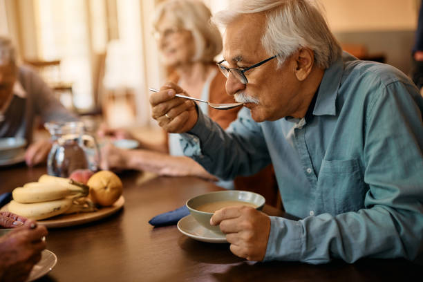 senior man eating lunch at nursing home. - senior adult nursing home eating home interior imagens e fotografias de stock