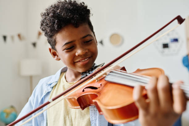 African little boy playing violin at home Smiling African boy playing violin at home during lesson juvenile musician stock pictures, royalty-free photos & images