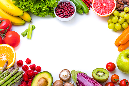 Top view of various multicolored fruits and vegetables disposed at the borders of the image on a frame shape leaving a useful copy space at the center on white background