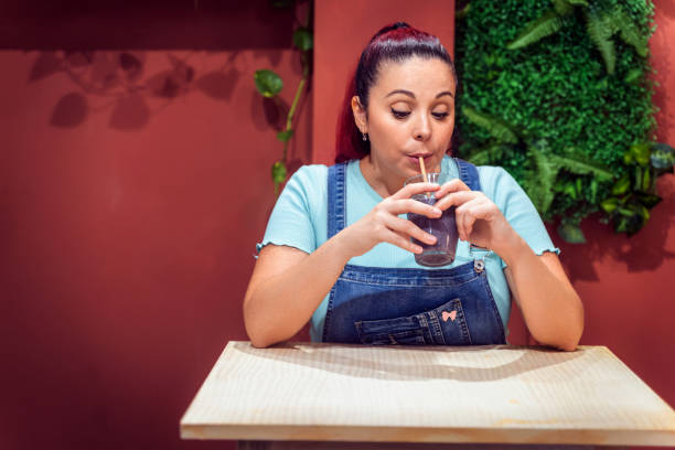 istock Young woman drinking a fresh smoothie while sitting in a cafe. 1413582747