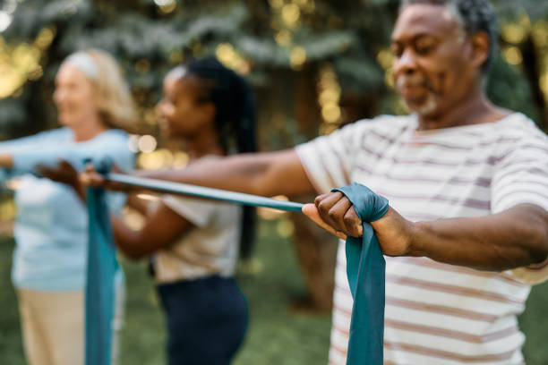 istock Close up of black mature man practicing with power band on exercise class in nature. 1413584038