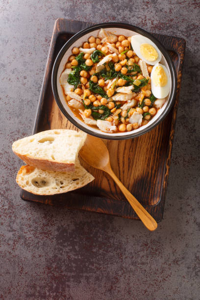 istock Spanish Easter dish called potaje de vigilia using cod with chickpeas, smoked paprika and spinach close-up in a bowl on the wooden tray. Vertical top view 1413585019