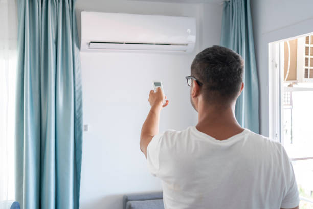 Air Conditioning System Man Turning On Air Conditioner With Remote Controller In Living Room remote controlled stock pictures, royalty-free photos & images
