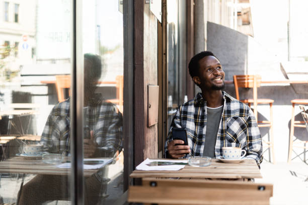 istock Happy African American relaxing at the cafe and using smartphone 1413585940