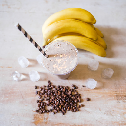 Ice coffee with banana flavor on table with ingredients around.