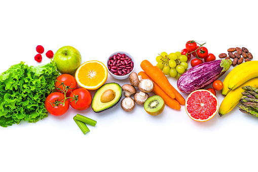 Top view of various multicolored fruits and vegetables disposed side by side at the center of the image on a stripe shape leaving a useful copy space at the top and at the bottom on white background