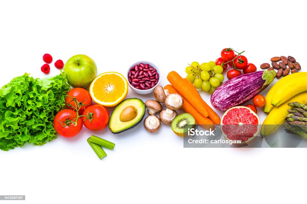 Fresh multicolored fruits and vegetables on white background Top view of various multicolored fruits and vegetables disposed side by side at the center of the image on a stripe shape leaving a useful copy space at the top and at the bottom on white background Vegetable Stock Photo