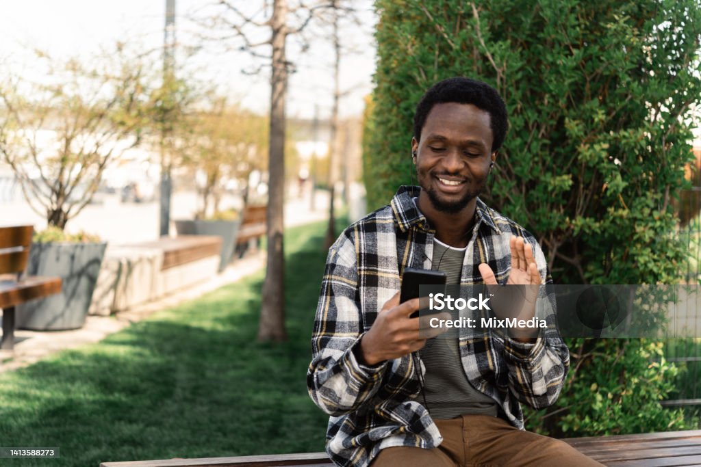 African American young man enjoying music and making a video call Portrait of a young African American man listening to music and enjoying outdoors 25-29 Years Stock Photo
