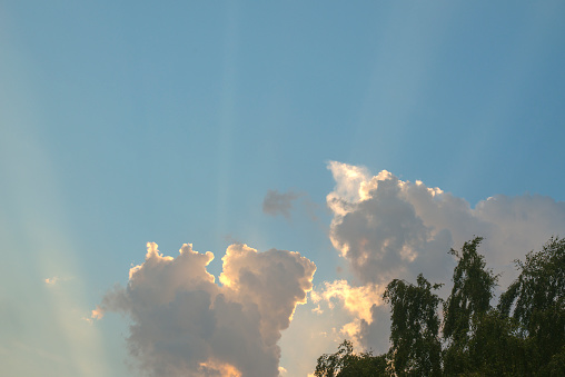 Rift between shadowy cloud at left and towering cumulus cloud at right on a summer evening, for background or element with motifs of difference, instability, changeability