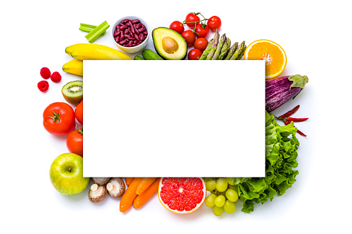 Top view of various multicolored fruits and vegetables isolated on white background and disposed at the center of the image with a white billboard on top leaving a useful copy