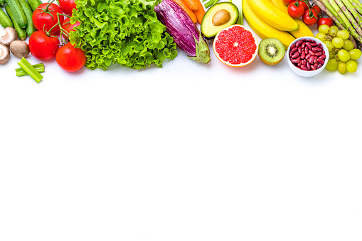 Top view of various multicolored fruits and vegetables disposed side by side at the top of the image on a stripe shape leaving a useful copy space at the bottom on white background