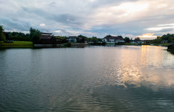istock Tranquil lake or river at sunset surrounded by houses 1413589871