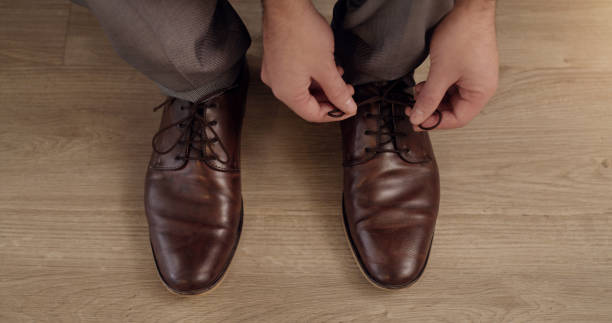istock Trendy, elegant and stylish man tying shoelaces and getting dressed for an interview. Closeup of a fashionable male putting on shoes while getting ready and preparing for a corporate office job 1413589878
