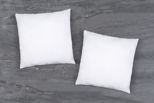 Two classic white throw pillows resting atop an elegant gray marble background