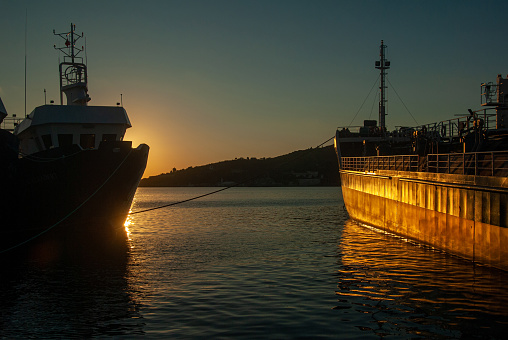 Silhouette of ships at sunset in the Black Sea and their reflection in the sea