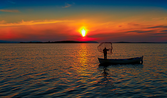 Silhouette scene of fishing boats on the sea with golden sunlight in the morning