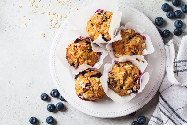 wegańskie płatki owsiane, banan, babeczki jagodowe na szarym tle. deser na bazie roślin. - muffin blueberry muffin blueberry food zdjęcia i obrazy z banku zdjęć