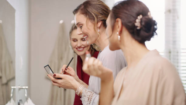 grupo de mujeres damas de honor felices, hermosas y elegantes preparándose, maquillándose y vistiéndose en el baño para una boda. mujeres jóvenes y bonitas modernas que se ponen cosméticos en un espejo - ceremonial makeup fotografías e imágenes de stock