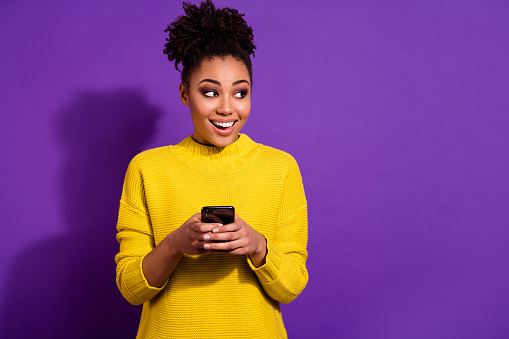 Photo of cheerful lady look interested empty space hold telephone blogging isolated on violet color background.