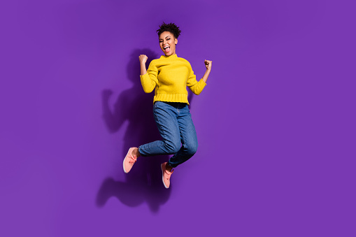 Full size photo of delighted nice person raise fists celebrate success jump isolated on violet color background.