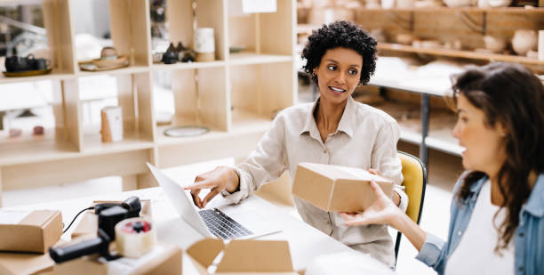 Female online store owners preparing some orders for shipping Female online store owners preparing orders for shipping in their warehouse. Two businesswomen packing some of their products into boxes. Female entrepreneurs running an e-commerce small business. shipping department stock pictures, royalty-free photos & images