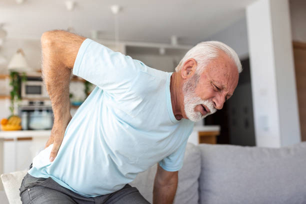 背中に触れ、腰痛、坐骨神経痛、座りがちな生活習慣の概念に苦しんでいる年配の男性。脊椎の健康問題。医療・保険 - arthritis osteoporosis pain backache ストックフォトと画像