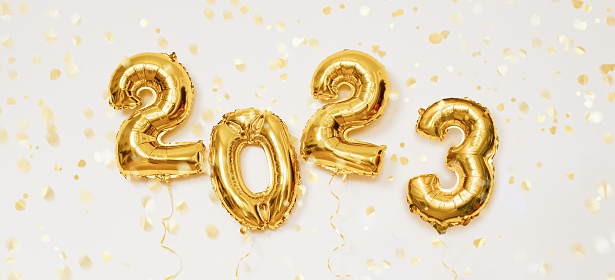 2022 golden foil balloons with champagne bottle and confetti. Happy new year and festive concept. Top horizontal view copyspace.