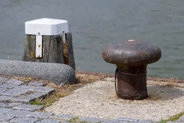 Wooden bollard and steel bollard in a harbor in the north of the Netherlands