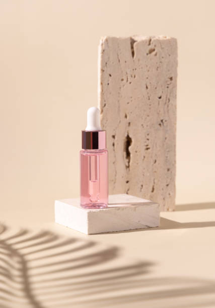 istock Dropper Bottle on travertine stone and palm leaf shadow on light yellow 1413600358