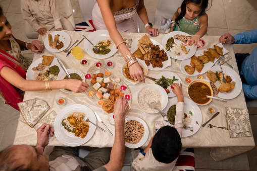 An aerial view of a family getting together to celebrate Diwali. The table of the family dining room in their home in the North East of England has been set for all of the family and has lots of tasty traditional foods for them all to try.