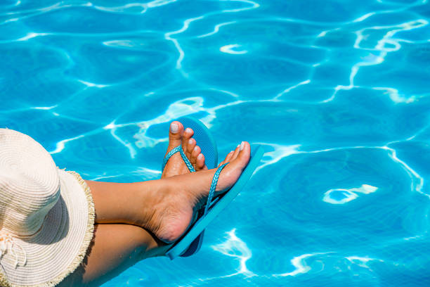 Woman foot with blue flip flops by the pool Close up of woman foot with blue flip flops by the pool. feet closeup woman wearing flip flops stock pictures, royalty-free photos & images