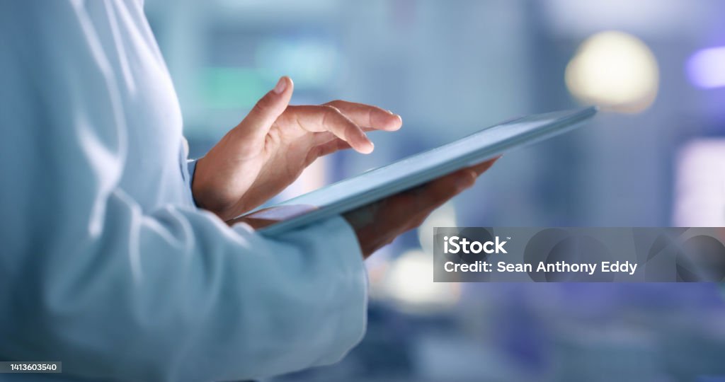 Doctor, researcher or scientist browsing the internet on a tablet for information while working at a lab, science facility or hospital. Expert, medical professional or surgeon searching the internet Healthcare And Medicine Stock Photo