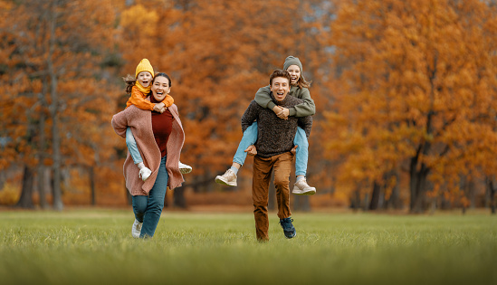 Happy family on autumn walk! Mother, father and daughters walking in the Park and enjoying the beautiful nature.