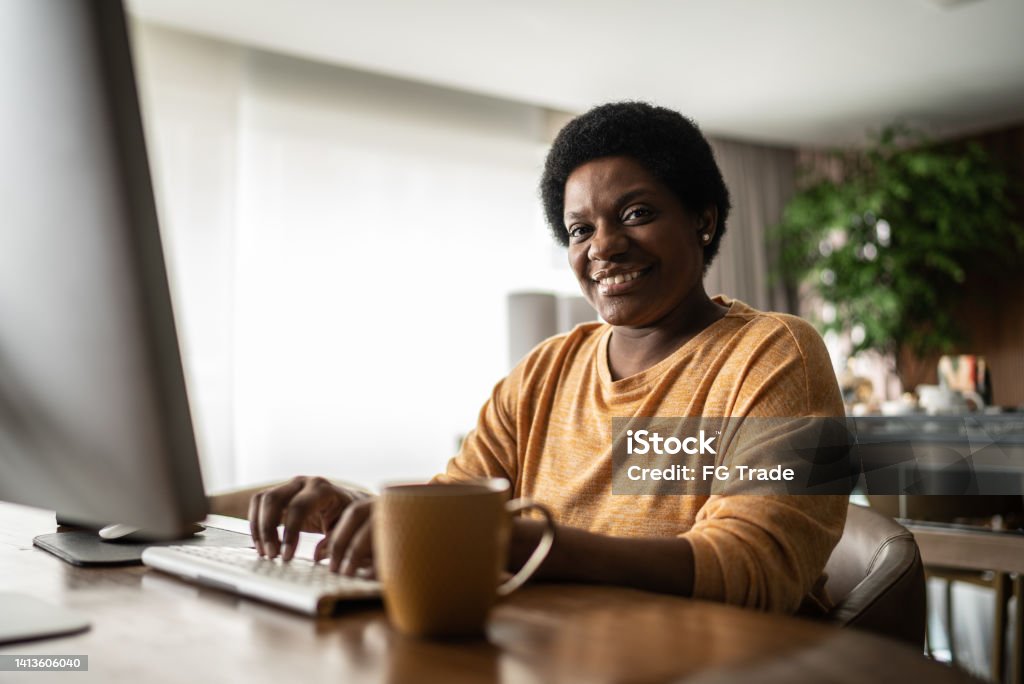 Retrato de uma mulher madura que usa o computador em casa - Foto de stock de Brasil royalty-free