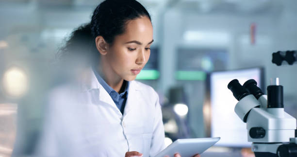 ricercatore scientifico concentrato e serio che legge informazioni su un tablet in un laboratorio. studente di scienze che studia i dati su un tablet portatile in un laboratorio mentre si prepara per un esperimento. - trainee computer medical student student foto e immagini stock