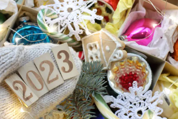 number 2023 on a knitted mitten against the background of Christmas tree decorations close-up