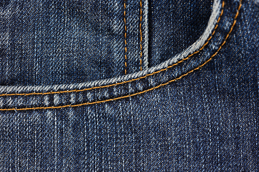 Focus-stacked macro photo of denim blue jeans with brass button and zipper detail.